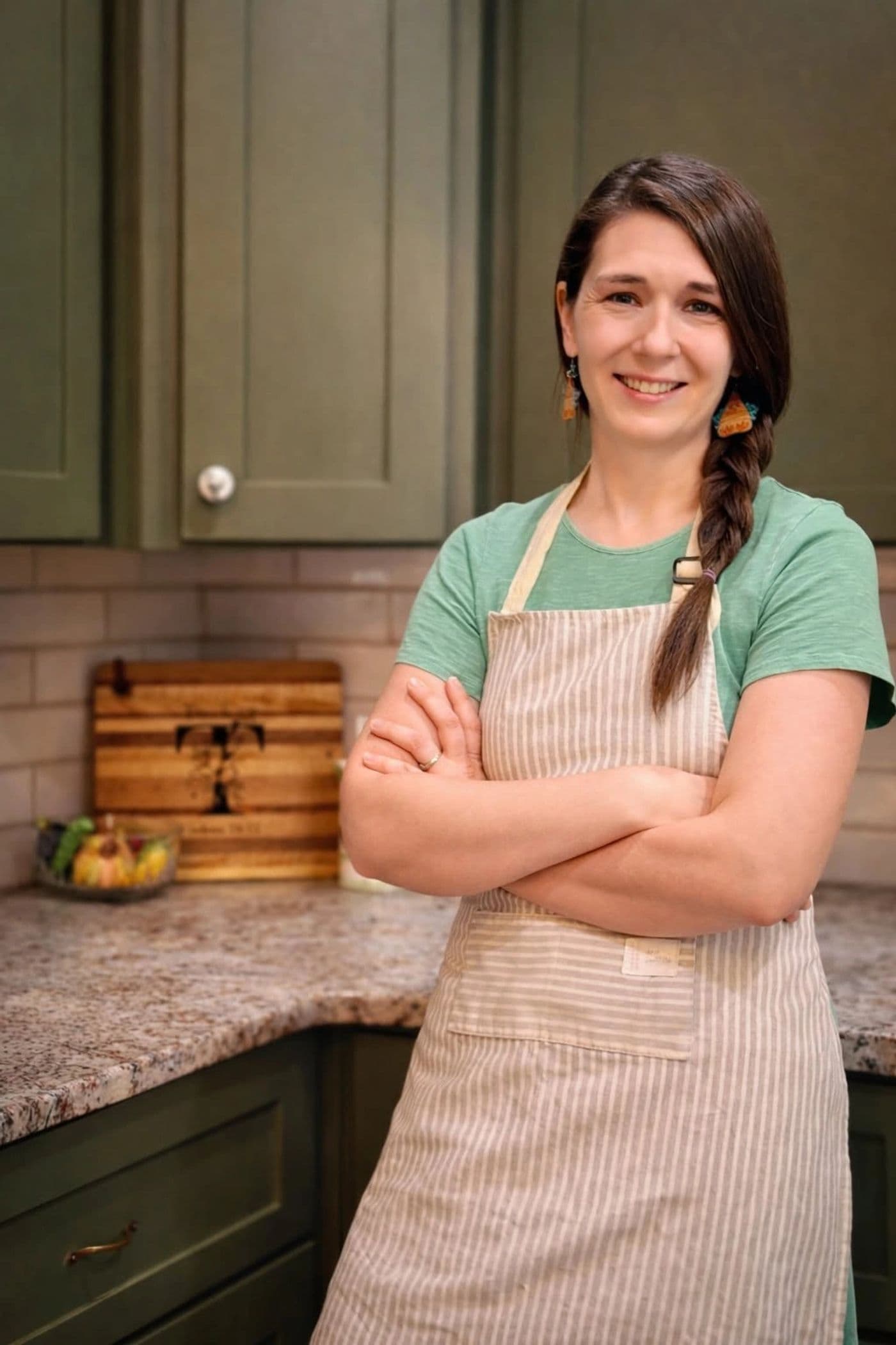 Amanda Tucker standing in her kitchen, arms crossed, wearing a striped linen apron